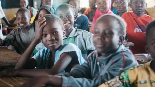 Lächelnde Schüler in einem Klassenzimmer in Burkina Faso, die Freude am Lernen ausstrahlen.