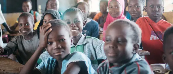 Lächelnde Schüler in einem Klassenzimmer in Burkina Faso, die Freude am Lernen ausstrahlen.