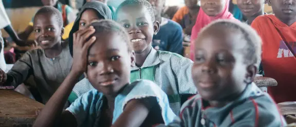 Lächelnde Schüler in einem Klassenzimmer in Burkina Faso, die Freude am Lernen ausstrahlen.