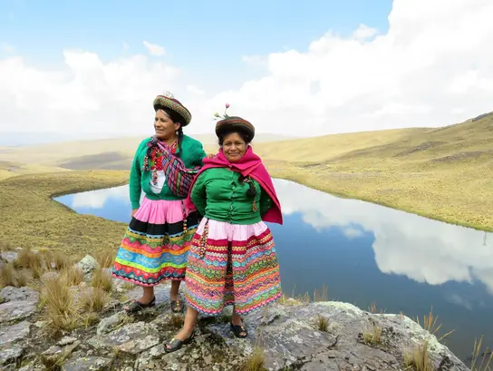 Magdalena y Marcela Machaca frente a un estanque de agua de lluvia