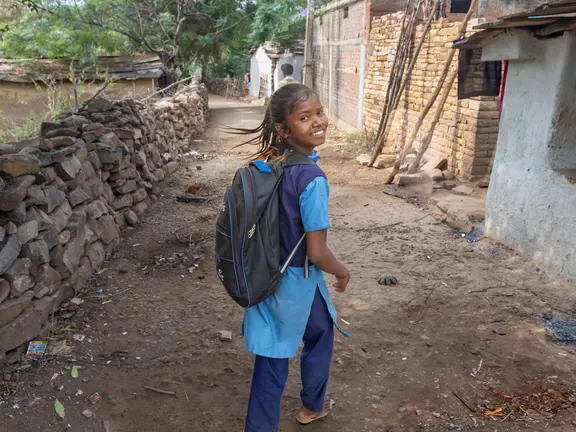  Ein Mädchen in Schuluniform schaut über die Schulter und lächelt in die Kamera.