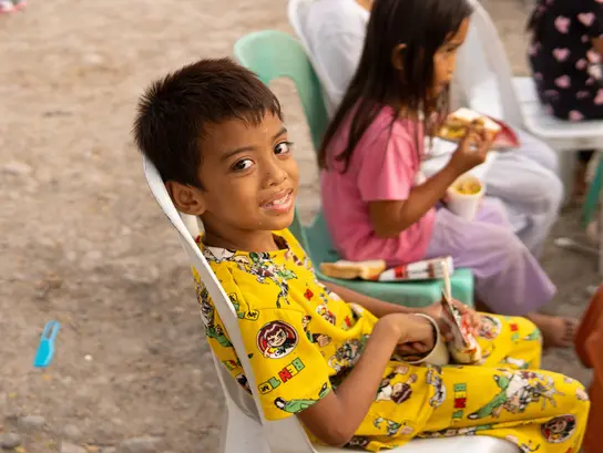 Un niño filipino come y espera a que comience una función teatral a cargo de una organización asociada de Terre des Hommes .