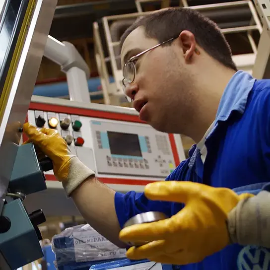 | © Terre des Hommes, Florian Kopp Ein Mann mit Behinderung bedient eine Maschine in einer Volkswagen-Fabrik in Argentinien.