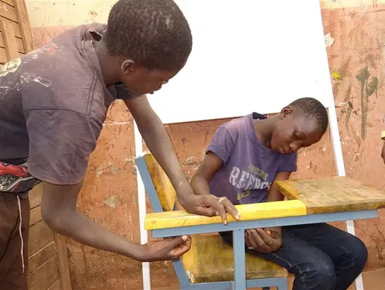 | © Terre des Hommes Mali: Zwei Jungen lösen gemeinsam eine Aufgabe im Schreiner-Handwerk.