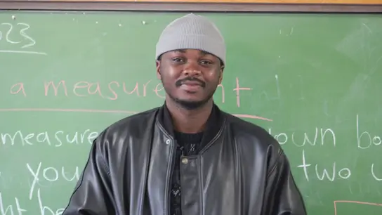 Der Lehrer Randry steht vor einer Schultafel in einer Schule in Südafrika. 