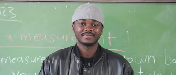 Der Lehrer Randry steht vor einer Schultafel in einer Schule in Südafrika. 