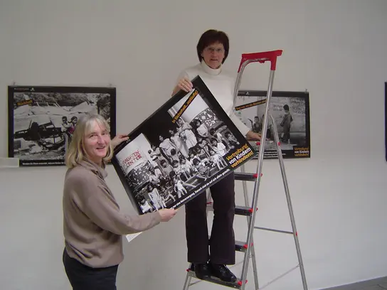 2 Mitglieder hängen Bilder für eine Ausstellung auf