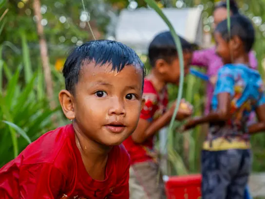A dripping wet boy looks into the camera; other children are in the background