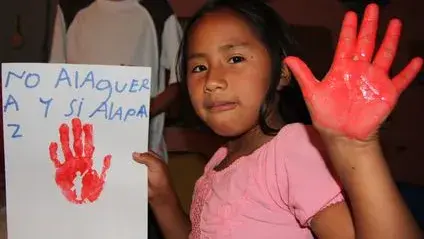 The image shows a Colombian girl with a red painted hand on the occasion of Red Hand Day.