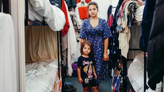 Eine Frau und ein Kind in einem Zimmer mit Etagenbetten