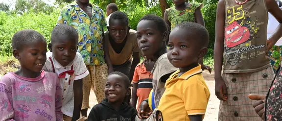 Sechs Kinder aus dem Südsudan posieren für ein Gruppenbild. Sie sind draußen und haben bunte Kleidung an.