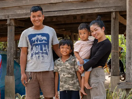 Eine Familie aus Kambodscha lächelt in die Kamera. Vater, Mutter und zwei Kinder.