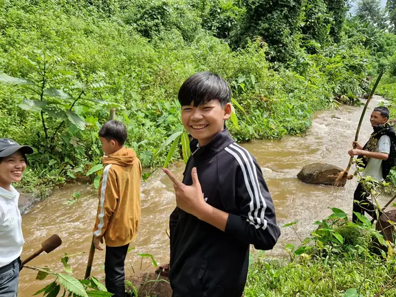 Kinder stehen mit Stöcken vor einem Fluss