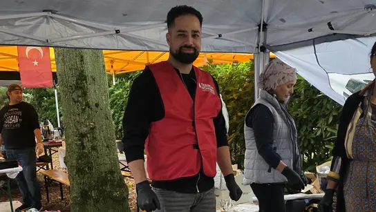 TDh Ehrenamtlicher bei einem Aktionsstand mit selbst gekochtem Essen und Aktionsbroschüren