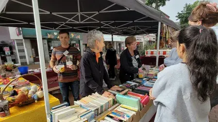 An ihren Flohmarktstand stehen Ehrenamtliche von Terre des Hommes. Sie sind im Gespräch mit Passanten.