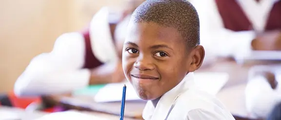Lächelnder Junge in Südafrika. Ihr Erbe stärkt Kinder.