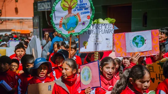 Kinder aus Bolivien demonstrieren mit Schildern in der Hand und roter Kleidung für Kinderrechte.