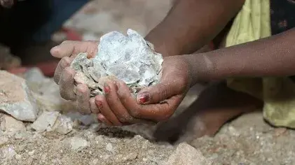 Das Bild zeigt Kinderhände, die das Glimmermaterial Mica halten