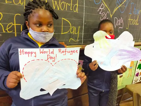 | © Three2Six Südafrika: Aktion von Kindern zum Weltflüchtlingstag. Mädchen halten selbst gemalte Plakate hoch.