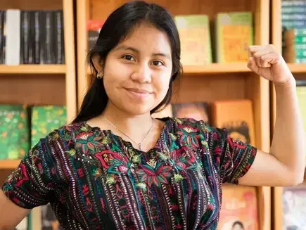 A girl with her arm bent upwards makes a gesture of strength