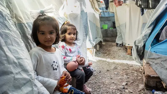 Zwei Kinder zwischen Zeltwänden und hängender Wäsche