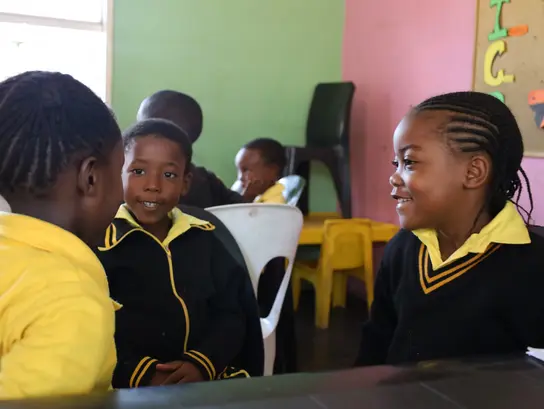 Mehrere Jungs aus Südafrika sitzen im Klassenraum und unterhalten sich fröhlich.