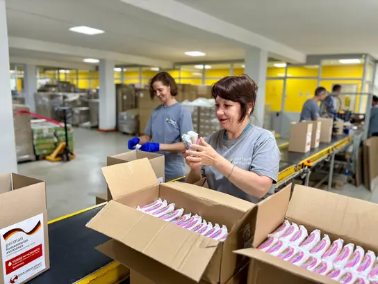 Helferinnen packen Lebensmittel- und Hygienepakete