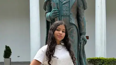 Mädchen im Teenager-Alter namens Shantal aus Venezuela steht vor Statue in Innenhof. 