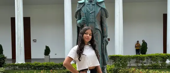 Mädchen im Teenager-Alter namens Shantal aus Venezuela steht vor Statue in Innenhof. 
