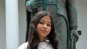 Mädchen im Teenager-Alter namens Shantal aus Venezuela steht vor Statue in Innenhof. 