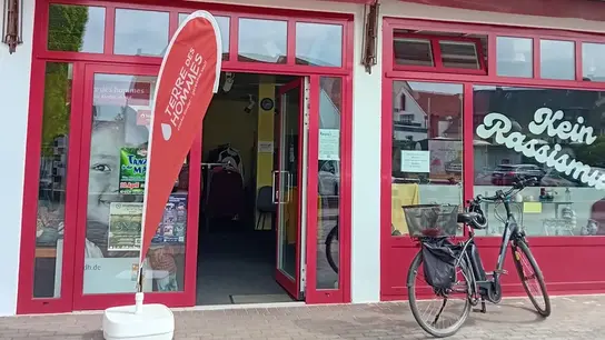 Entrada de la tienda con una bicicleta delante de la puerta y la bandera de playa de TDH.