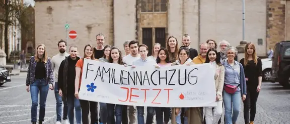 Das Bild zeigt Terre des Hommes-Aktivist*innen bei einer Demo mit einem Banner "Familiennachzug - jetzt!"