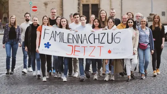 La imagen muestra a Terre del activista de Hommes en una demostración con una pancarta &quot;Reunificación familiar, ¡ahora!&quot;