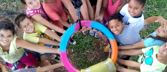Das Bild zeigt Kinder im Projekt CEDECA in Brasilien, die in der Mitte einen Ring halten