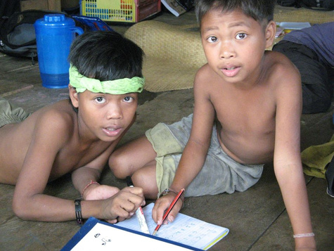 Zwei Jungen der Orang Rimba vor einem Schreibheft.
