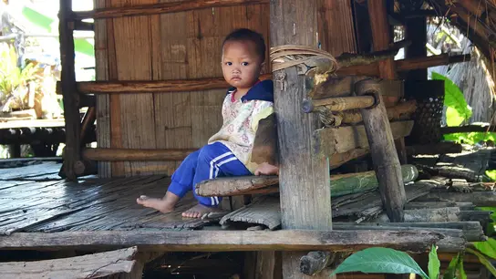 Thailand: Ein Junge sitzt auf einer Veranda. 