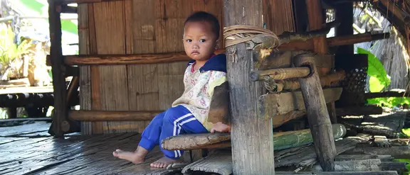 Thailand: Ein Junge sitzt auf einer Veranda. 