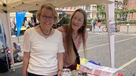 Se puede ver a miembros de Terre des Hommes detrás del puesto de información rojo en Wilhelmsplatz, frente a una iglesia en Heidelberg Weststadt.